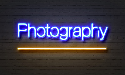 Photography neon sign on brick wall background.