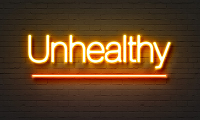 Unhealthy neon sign on brick wall background.