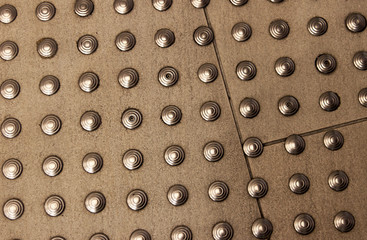 Metal rivets attached to the concrete surface. Abstract background.