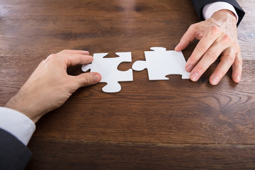 Two Businesspeople Connecting Puzzle Pieces