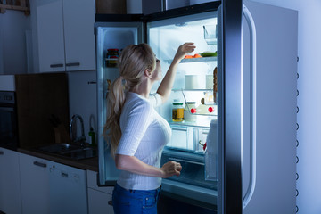 Fototapeta na wymiar Woman Searching For Food In Refrigerator
