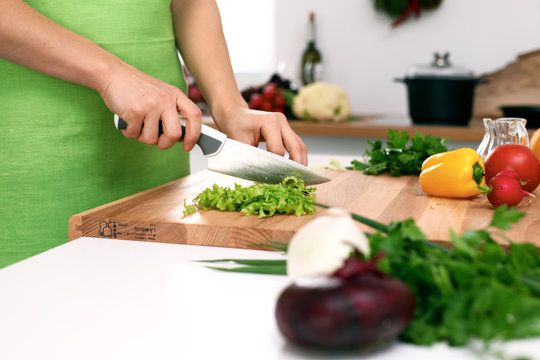 Close up of  woman's hands cooking in the kitchen. Housewife slicing ​​fresh salad. Vegetarian and healthily cooking concept