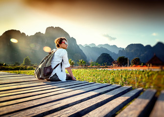 Fototapeta premium Happy tourist woman meets a sunset overlooking the mountains and fields. Travelling in Asia