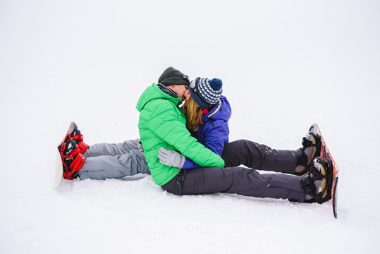 boy and girl kissing sitting on snow