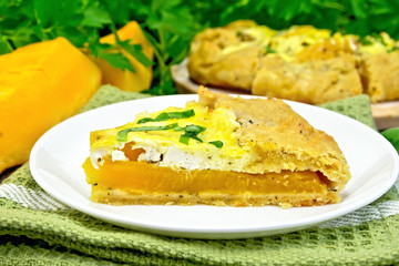 Pie of pumpkin and cheese in white plate on dark board