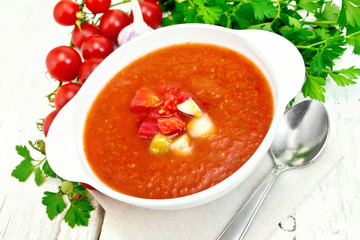 Soup tomato in white bowl with vegetables on board