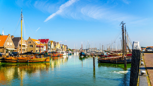 Sail boats and motor boats moored in a part of the harbor overtaken by algae in the historic fishing village of Urk in the Netherlands
