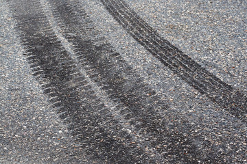 Tire tracks and footstep on the asphalt road.