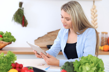 Young  woman is making online shopping by tablet computer and credit card. Housewife found new recipe for  cooking in a kitchen