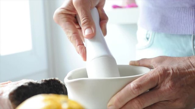 Close-up of woman's hands using mortar and pestle to grind ingredients