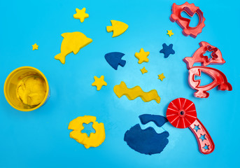 Fototapeta na wymiar Set of play dough and plastic cutting block on blue background