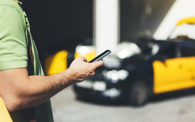 Man pointing finger on screen smartphone on background yellow taxi, tourist hipster using in hands...