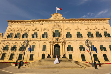 Obraz premium Bride and groom in front of a big building