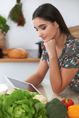 Young hispanic  woman is making online shopping by tablet computer and credit card. Housewife found new recipe for  cooking in a kitchen