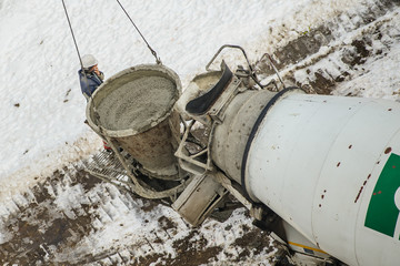 Concrete mixer truck pouring liquid concrete into the tower crane bucket