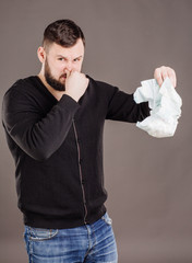 father holding dirty dirty diaper in one hand fingers over black background.