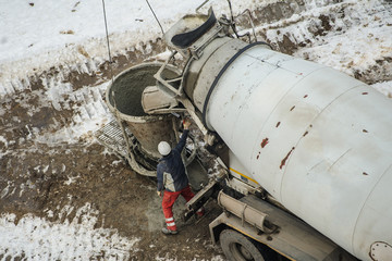 Concrete mixer truck pouring liquid concrete into the tower crane bucket