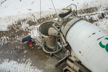 Concrete mixer truck pouring liquid concrete into the tower crane bucket © Med Photo Studio
