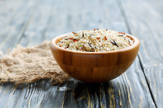 White, red, brown and wild rice in a wooden bowl.