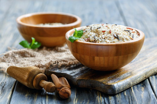 Wooden bowls with white, brown, red and wild rice.