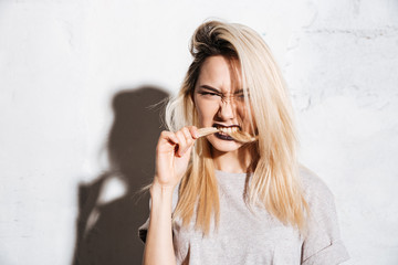 Angry beautiful young woman biting her long blonde hair