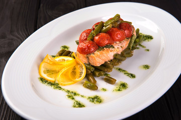 Grilled trout with tomatos leguminous beans and lemon on white plate. close up