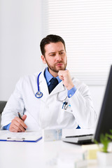 Pensive Male doctor watching computer monitor
