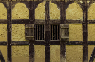 Wooden shutters in the wall of an old adobe house