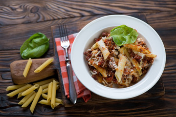 White plate with italian ziti on a rustic wooden surface