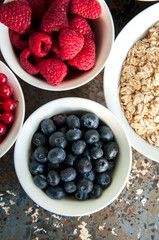 Oat, berries in bowls on a rusty background