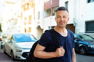 Male outdoor street portrait. Mid adult man walking at summer city Saint Jean de Luz streets, France.