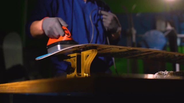 Grind edge on a snowboard in the service. Paraffin board. snowboard repair