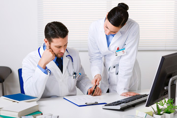 Two doctors discussing patient notes in an office
