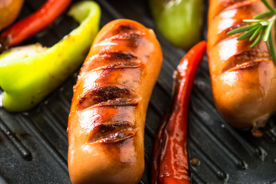 Fried sausages with  vegetables in grill pan at black background