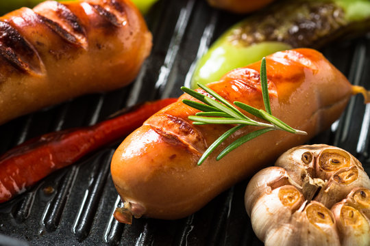 Fried sausages with  vegetables in grill pan at black background