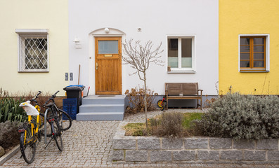 Tidy Facade of Townhouse with Wooden Front Door and Parked Bicycles - obrazy, fototapety, plakaty