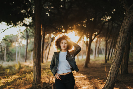 Chica paseando por el bosque feliz y con el atardecer detr&aacute;s