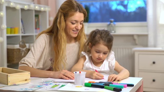 Happy family. Mother and daughter are learning to write. Adult woman teaches child the alphabet.