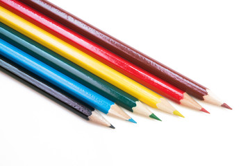 Fototapeta premium Six colored pencils on a white background. Dark blue, blue, green, yellow, red and brown. Bright colors. Back to school.