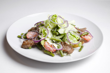 Salad with beef roast beef and vegetables on a white background