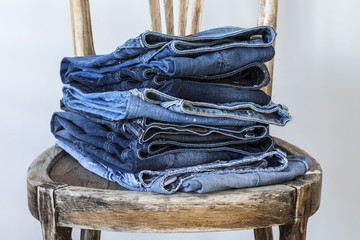 Stack of jeans on wooden chair