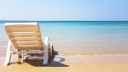 Obraz premium white armchair on the wet beach in sunny time