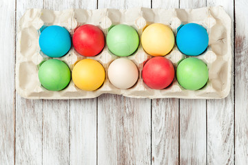 Colorful easter eggs in a tray over wooden background. Space for text. Easter card.