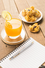 Notebooks with snacks and orange juice on a wooden table backgro