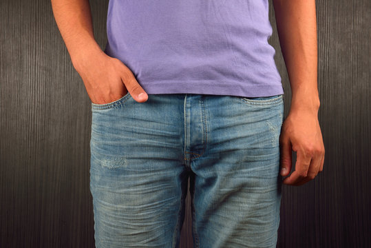 Young man with right hand in the pocket of his blue jeans, wearing purple t-shirt. Clothing design concept