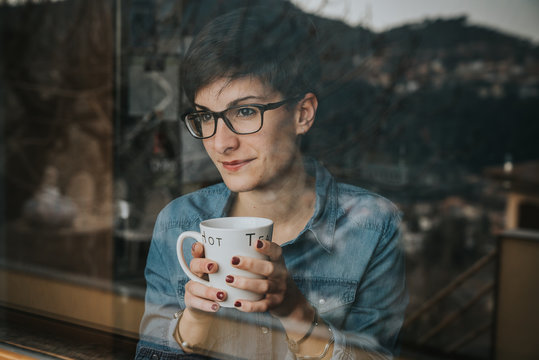 Chica mirando por la ventana con el t&eacute;