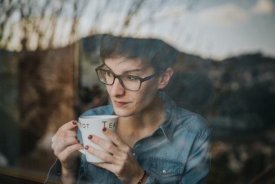 Chica mirando por la ventana con el t&eacute;