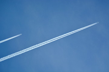 a pair of aircraft flying in the clear sky diagonally leaving a white trail