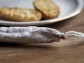 Fuet - Spanish sausage - on wood background with unfocused bread
