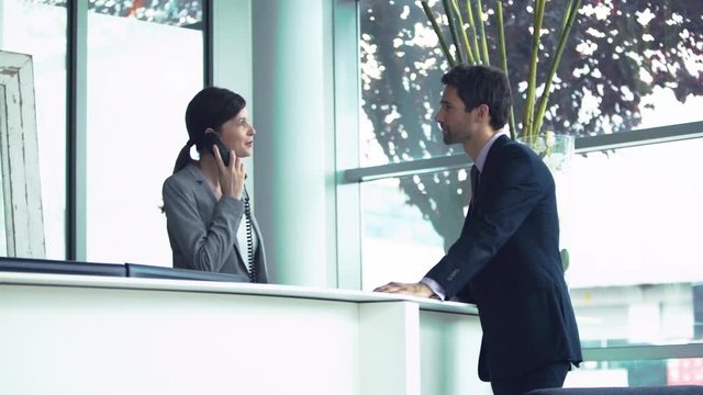 Hotel receptionist making call on customer's behalf